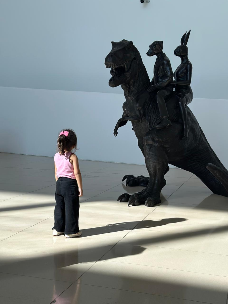 Child looking at a large dinosaur sculpture inside the Heydar Aliyev Center in Baku