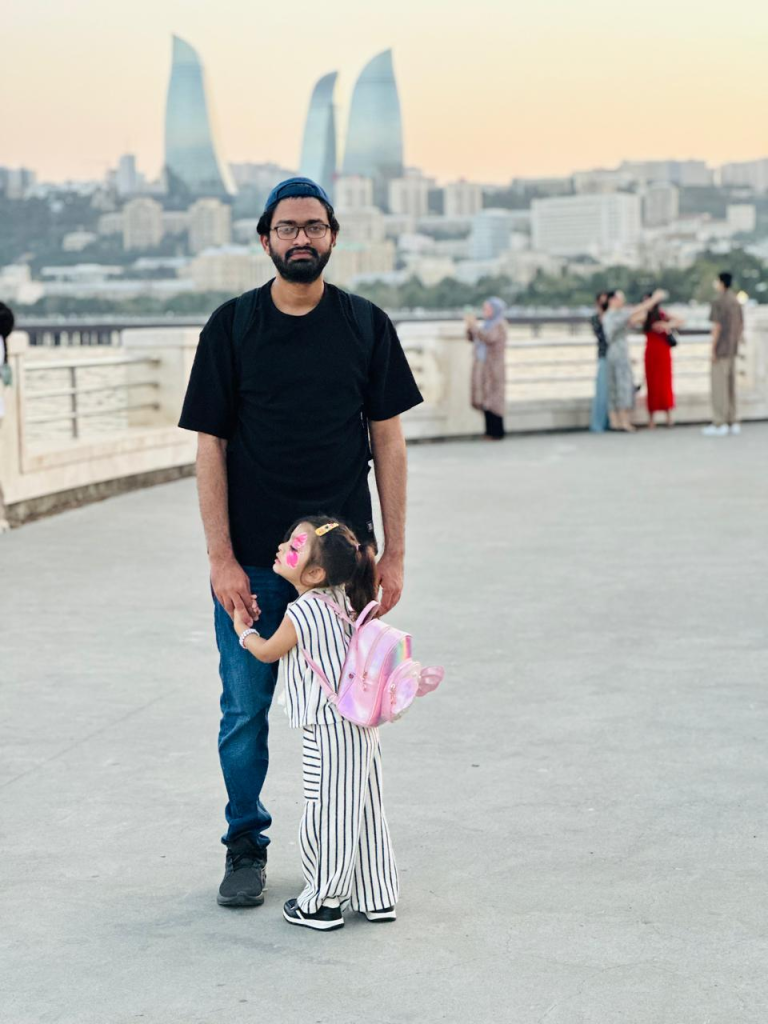 Faisal and his daughter enjoying an evening walk along Baku Boulevard with the Flame Towers in the background
