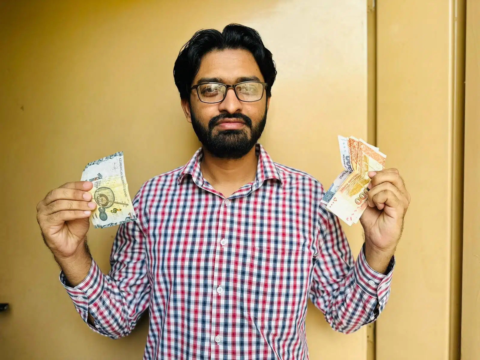 Faisal holding Pakistani rupees and Azerbaijani manat during a trip to Baku
