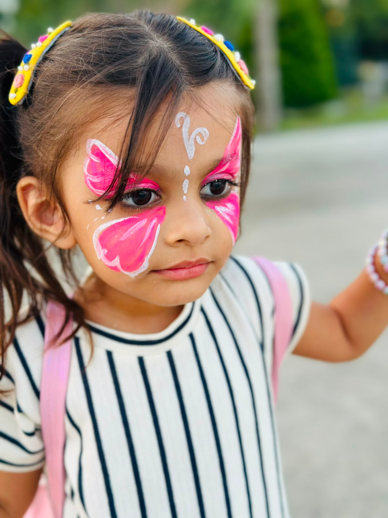 Fatima showing her colorful butterfly face paint at a shopping mall in Baku