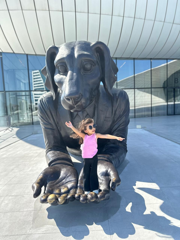 Fatima standing on a giant dog sculpture outside Heydar Aliyev Center in Baku