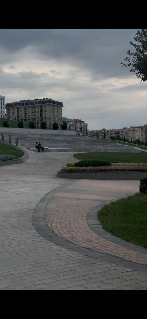 Green Park Baku, Azerbaijan, with landscaped walking paths, green lawns, steps, and surrounding buildings under a cloudy sky