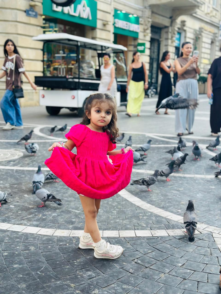 Zainab standing among pigeons on Nizami Street in Baku